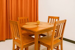 A wooden dining table with four chairs, a woven placemat, and a yellow object on the table. - Beachfront Apartment, Terrace Onto Sand Uroa Zanzibar (Uroa)