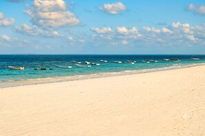 A beach with boats anchored in the water and a sandy shore. - Beachfront Apartment, Terrace Onto Sand Uroa Zanzibar (Uroa)