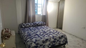 Une chambre à coucher avec un lit, des rideaux, une fenêtre et un radiateur.