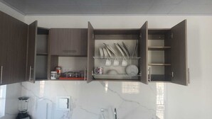 Une cuisine avec des placards ouverts, un plan de travail sur lequel se trouve un mixeur et un pare-feu en marbre.