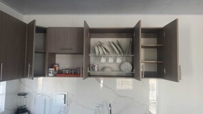 Eine Küche mit offenen Schränken, einer Arbeitsfläche mit einem Mixer und einer Marmor-Spritzschutzwand.