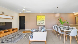 Una sala moderna con un sofá, una mesa de centro y un comedor con sillas y una mesa dispuesta para una comida.