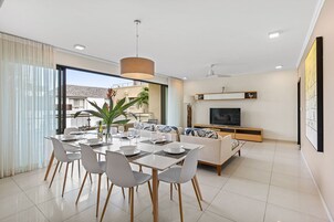 Una sala de estar moderna con comedor, un televisor de pantalla plana y un ventanal amplio.
