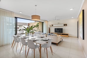 A modern living room with a dining area, a flat-screen TV, and a large window. - 17 Ocean Legend (Tamarin)