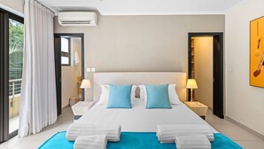 Habitación de hotel con una cama grande, dos lámparas de noche, un ventilador de techo y vistas al exterior.