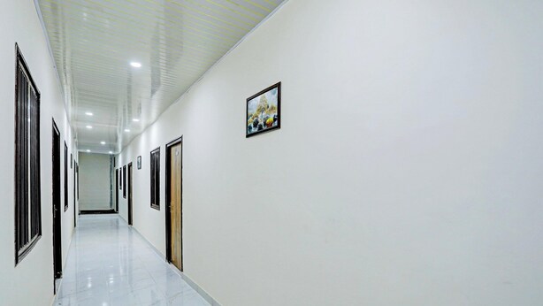 A long, narrow hallway with white walls and doors, leading to a room at the end. - Deluxe Lucknow Inn (Lucknow)