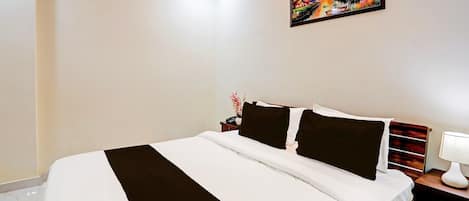 A hotel room with a bed, a nightstand, a lamp, and a painting on the wall.