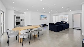 A modern living space with a dining area, a sofa, and a kitchen in the background. - Cozy Haven (Miami)