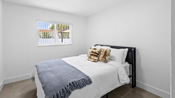 A bedroom with a bed, a window, and a ceiling light. - Cozy Haven (Miami)