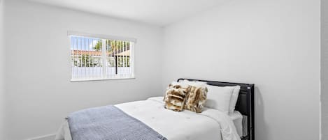 A bedroom with a bed, a window, and a ceiling light.
