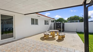 A covered patio area with a tiled floor, a small round table, and two chairs. - Cozy Haven (Miami)