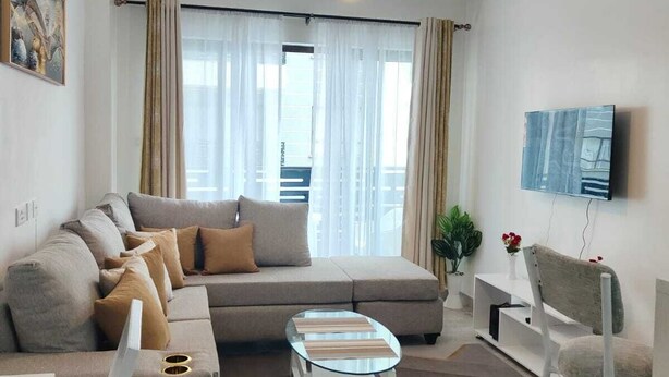 A modern living room with a sofa, coffee table, and a TV mounted on the wall. - The Enkang Urban Escape (Nairobi)