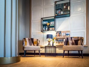 A room with two armchairs, a side table with a lamp, and a wall-mounted shelf with various items. - Ride, Unwind & Explore The Hague | Suite Stay | Museum Beelden aan Zee - 0.2 mi (Den Haag)