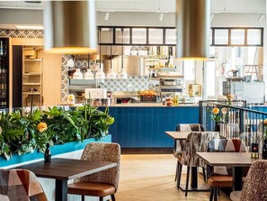 Ein Restaurant mit blauer Theke, Sitzbereich und Küche im Hintergrund.