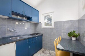 Eine Küche mit blauen Schränken, einer Spüle, einem Herd und einem Fenster.
