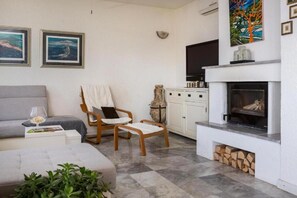 Ein Wohnzimmer mit Sofa, Sessel, Kamin und Fernseher.