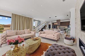 A spacious living room with two plush sofas, a coffee table, and a fireplace. A staircase leads to an upper level. - Villa Kim (Buje)