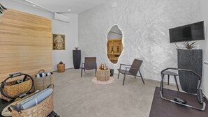 Ein modernes Interieur mit einer Holzvertäfelung, einer großen Steinwand mit Fernseher und einer Sitzecke mit Stühlen und einem kleinen runden Tisch.