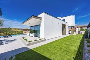 A modern house with a swimming pool, a well-maintained lawn, and a patio area. - Villa Kim (Buje)
