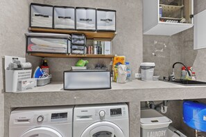 A modern kitchen with a built-in washer and dryer, a sink, and neatly organized storage cabinets. - Villa Kim (Buje)
