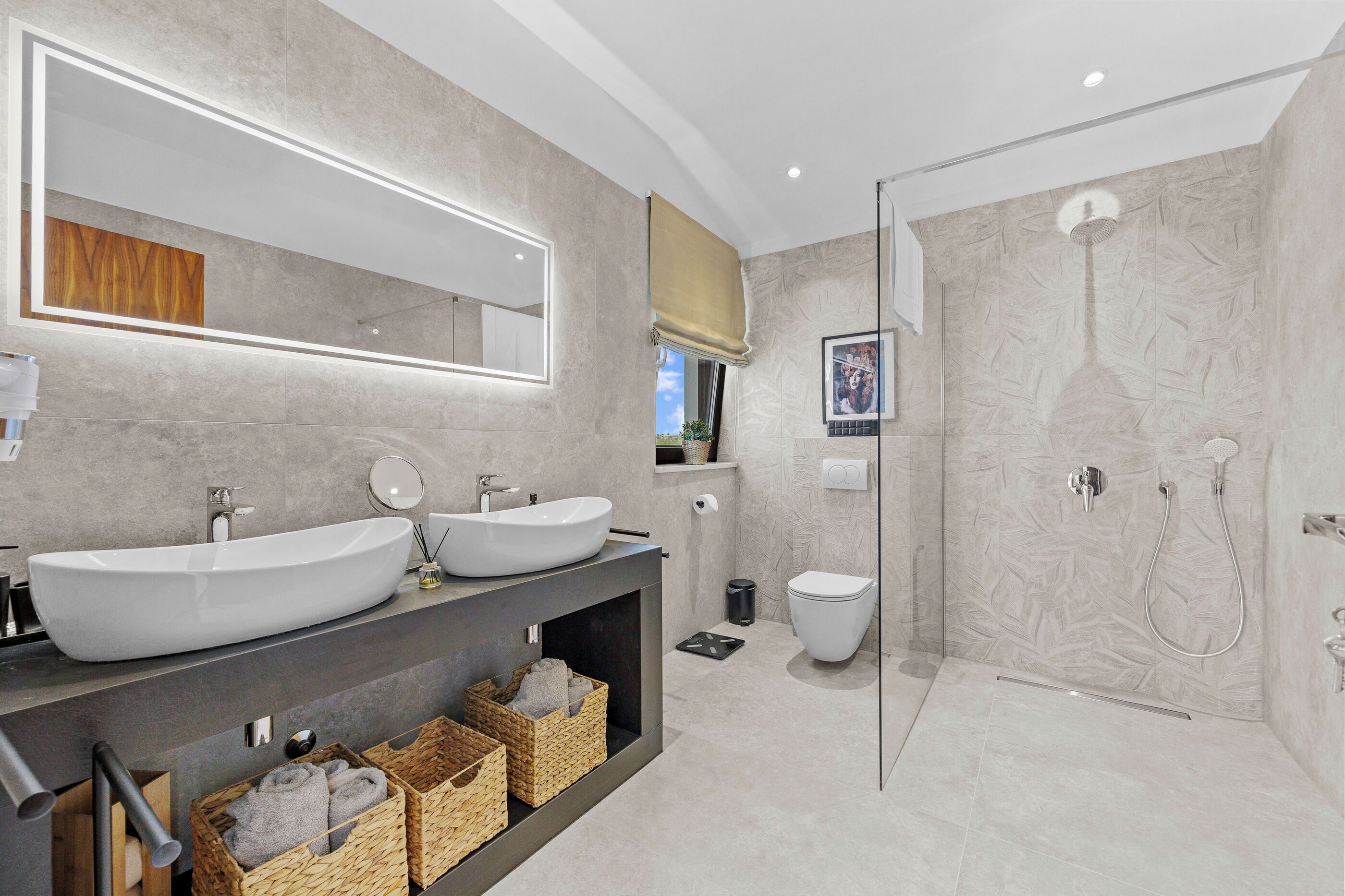 A modern bathroom with two sinks, a toilet, and a glass-enclosed shower.