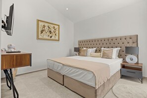A modern bedroom with a tufted headboard, a large bed, a bedside table with a lamp, a desk with a computer, and a framed artwork on the wall. - Villa Kim (Buje)