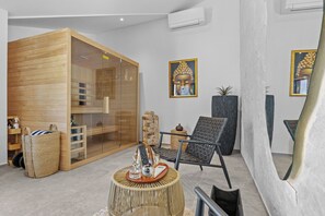 A modern spa room with a wooden cabinet, a black chair, a round wicker table, and two Buddha paintings on the wall. - Villa Kim (Buje)
