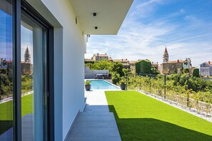 A modern building with a pool, green lawn, and a view of historic buildings in the background. - Villa Kim (Buje)