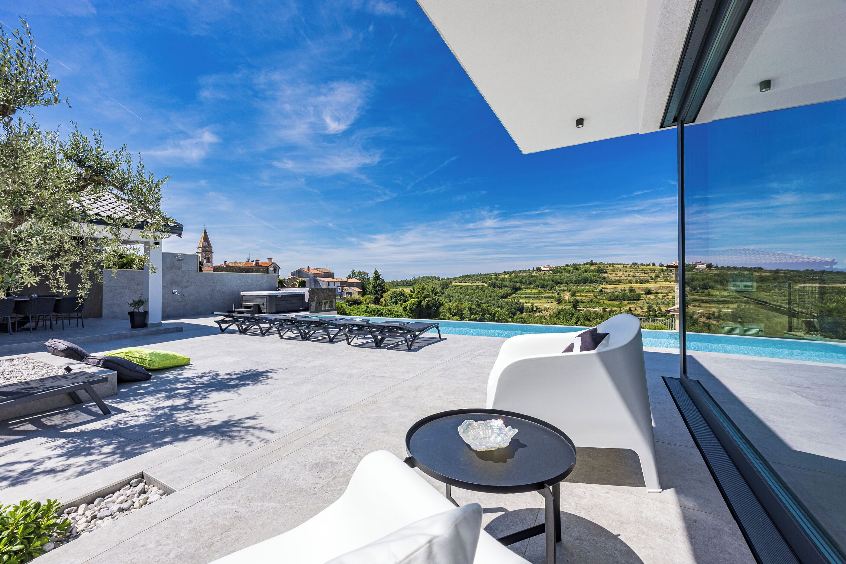 A modern outdoor patio with a pool, seating, and a scenic view.