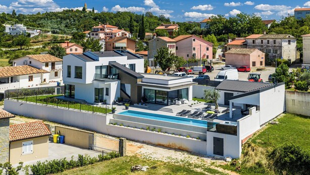 Ein modernes Haus mit Schwimmbad, umgeben von weiteren Häusern und Grünflächen.