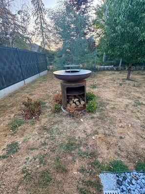 Un pati d'entrada amb una bústia envoltat per una tanca, un arbre petit i una zona enjardinada.