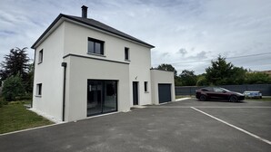 A modern two-story house with a garage, a driveway, and a parked car. - Vacation home 3 min from Le Mans 24H circuit with terrace, private garden, and Wi-Fi (Changé)