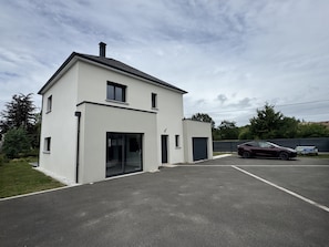 Une maison moderne à deux étages, dotée d’un garage, d’une allée et d’une voiture garée.