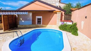 A swimming pool with a ladder, a door, and a small covered area with a bench. - House Cancin (Porec)