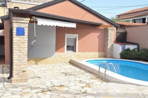 A residential property with a swimming pool, stone flooring, and a covered outdoor area. - House Cancin (Porec)