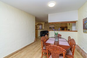 Ein Essbereich mit einem Holztisch und Stühlen, einer Blumenvase und einer Steinwand im Hintergrund.