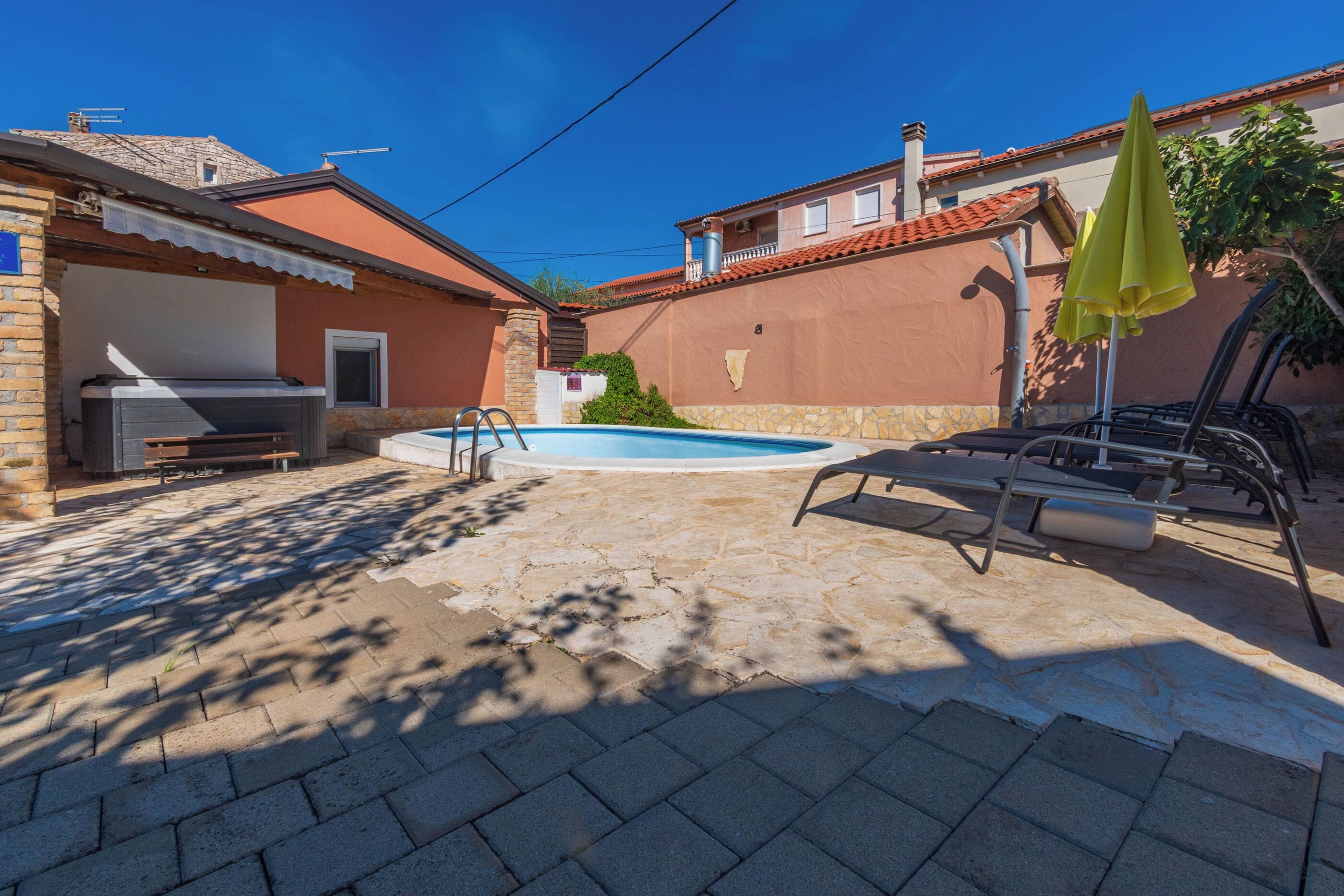 A backyard with a swimming pool, a barbecue area, and outdoor seating.