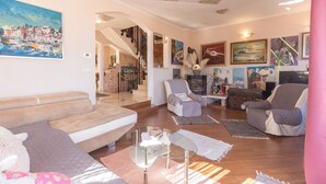 A living room with a sofa, armchairs, a glass coffee table, and artwork on the walls. - Apartments Emily (Opatija)