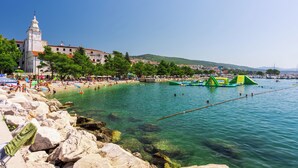 Eine Küstenlandschaft mit Strand, klarem Wasser und einem markanten weißen Gebäude mit Turm.