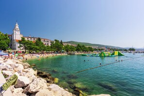 Eine Küstenlandschaft mit Strand, klarem Wasser und einem markanten weißen Gebäude mit Turm.
