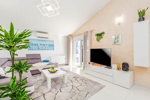 Ein modernes Wohnzimmer mit Sofa, Couchtisch, Fernseher und Zierpflanzen.