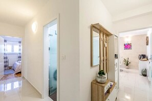A hallway with a mirror, a wooden console, and a door leading to a bathroom. - Apartment Kovacic (Pula)