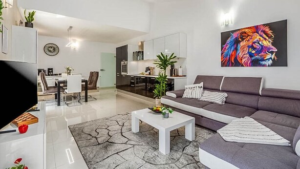 A modern living room with a grey sofa, a white coffee table, and a colorful abstract painting. - Apartment Kovacic (Pula)