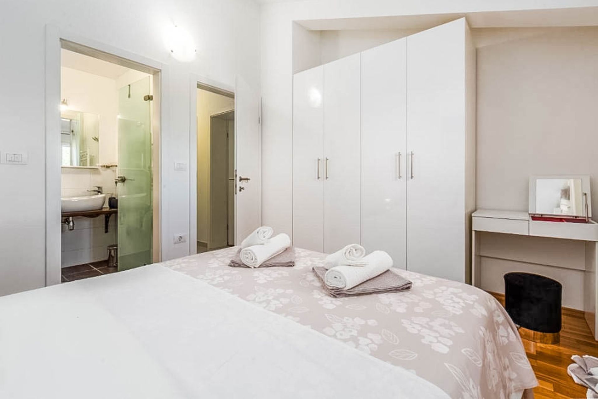 A hotel room with a bed, a wardrobe, a bathroom, and a small desk with a chair.