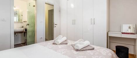 A hotel room with a bed, a wardrobe, a bathroom, and a small desk with a chair.