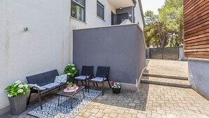 A patio with outdoor seating, a potted plant, and a patterned rug. - Apartment Kovacic (Pula)