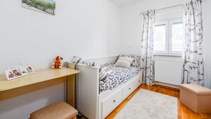 A bedroom with a bed, a desk, a chair, a small table, and a window with curtains. - Apartment Kovacic (Pula)