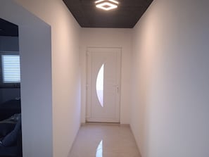 A hallway with a white door, a ceiling light fixture, and a tiled floor. - Apartment Anton (Selca)