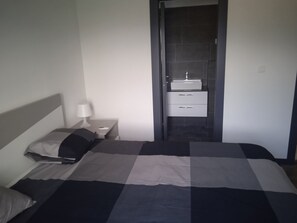 A hotel room with a bed, a nightstand with a lamp, and a bathroom with a sink and drawers. - Apartment Anton (Selca)