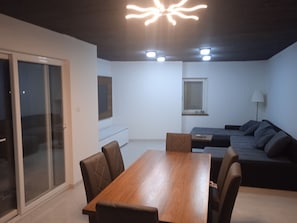 En moderne stue med et træspisebord, mørke sofaer og en loftslampe.